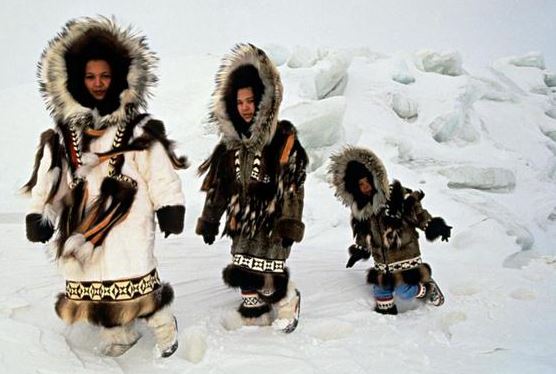 Esquimós caminhando sobre a neve.